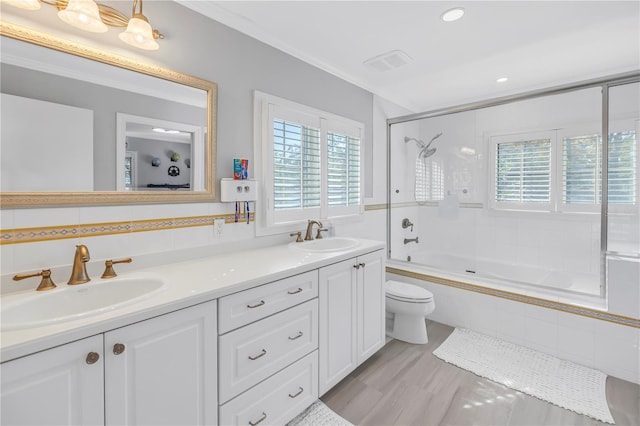 full bathroom with combined bath / shower with glass door, a sink, toilet, and double vanity