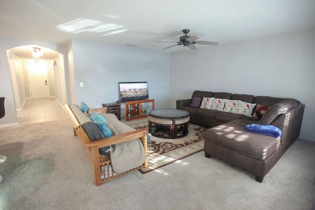 carpeted living area featuring arched walkways, ceiling fan, and tile patterned floors