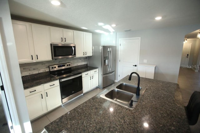 kitchen with stainless steel appliances, a sink, decorative backsplash, and light tile patterned floors