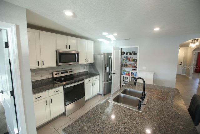 kitchen featuring arched walkways, light tile patterned flooring, stainless steel appliances, a sink, and decorative backsplash