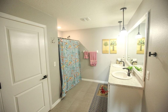 bathroom with tile patterned flooring, a sink, visible vents, and baseboards