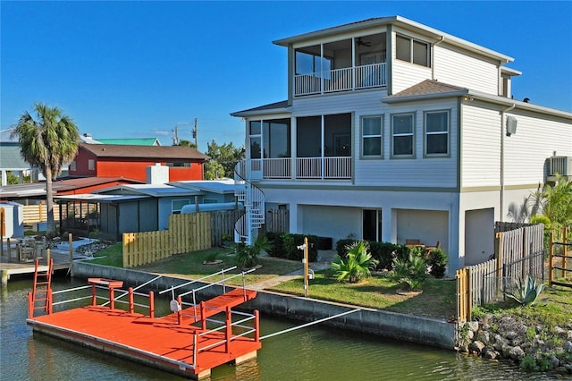 back of house featuring stairs, a water view, fence, and a sunroom