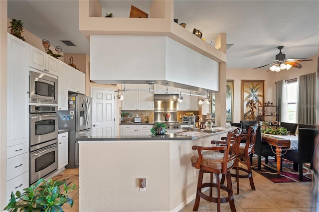 kitchen with a peninsula, visible vents, white cabinets, appliances with stainless steel finishes, and dark countertops