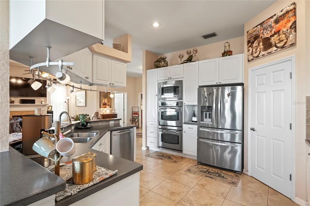 kitchen with dark countertops, visible vents, appliances with stainless steel finishes, white cabinets, and a sink