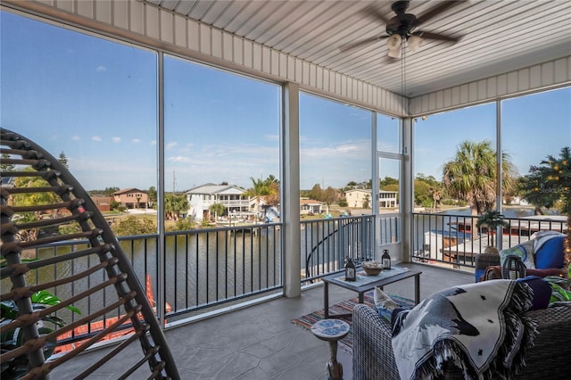 sunroom / solarium featuring a water view, ceiling fan, and a residential view