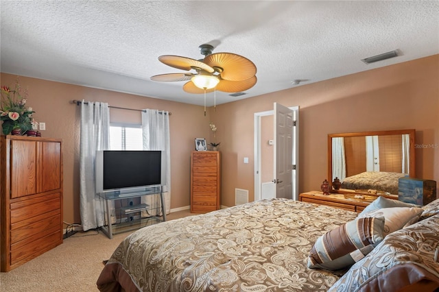 bedroom featuring visible vents, light carpet, and a textured ceiling