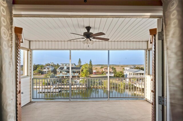 unfurnished sunroom featuring a water view and a ceiling fan