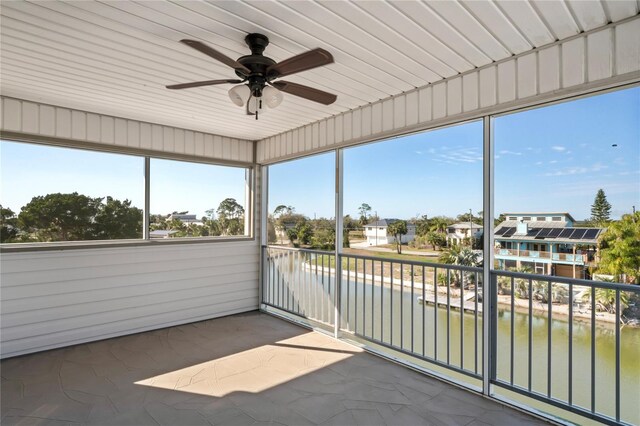 unfurnished sunroom featuring a water view and a ceiling fan