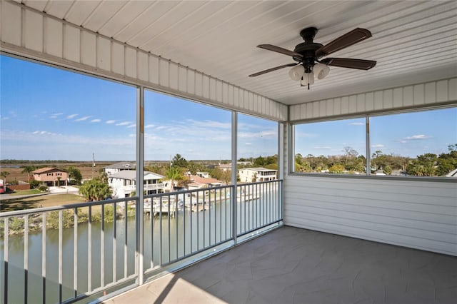 unfurnished sunroom featuring a water view, plenty of natural light, and a ceiling fan