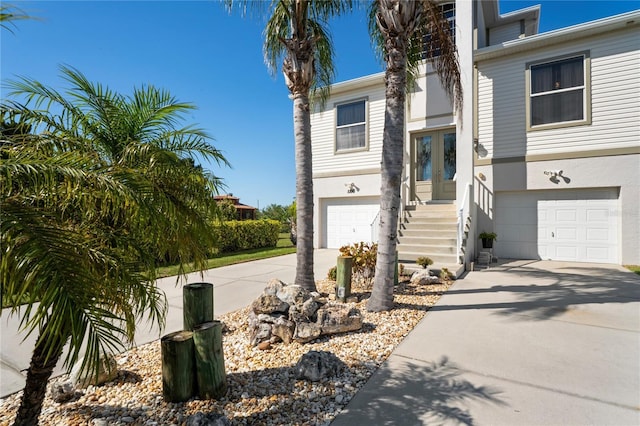 view of front facade featuring a garage, stucco siding, concrete driveway, and french doors