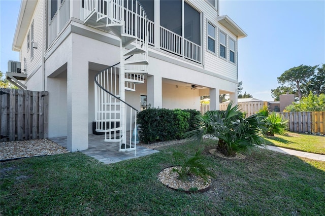 back of property with stairway, fence, a lawn, and stucco siding