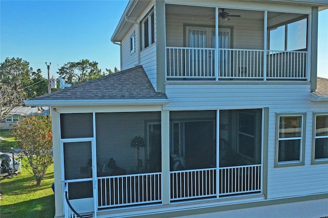 view of side of home with ceiling fan, a shingled roof, and a sunroom