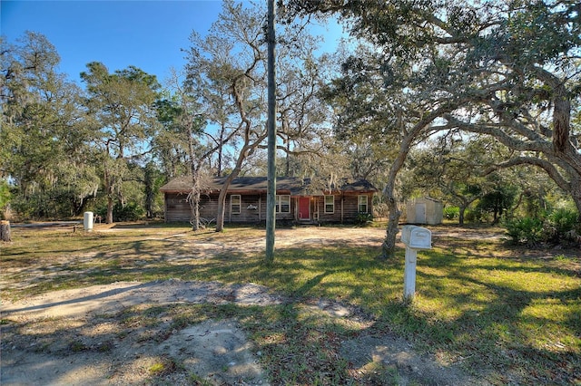 view of front facade featuring a storage shed, an outbuilding, and a front yard