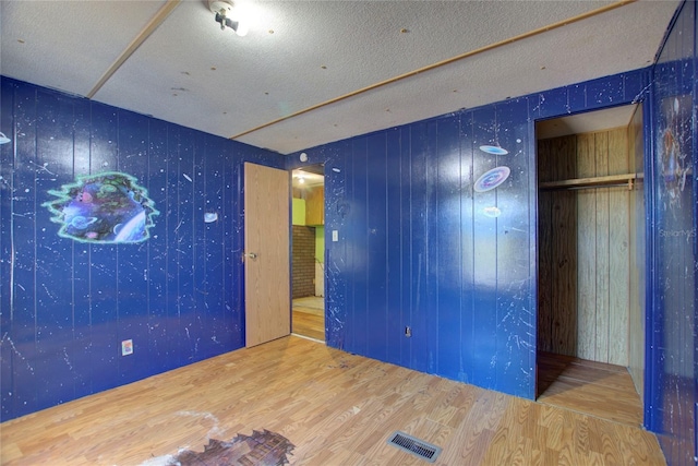 unfurnished bedroom featuring visible vents, a textured ceiling, and wood finished floors