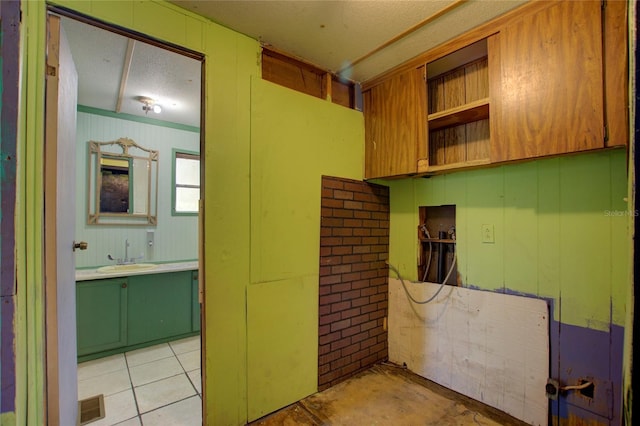 interior space with a textured ceiling, a sink, and visible vents