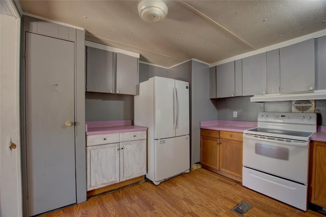 kitchen featuring white appliances, visible vents, light wood-style flooring, light countertops, and under cabinet range hood