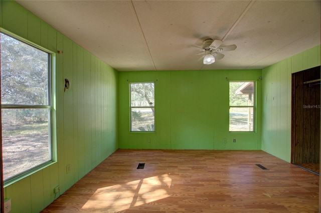 unfurnished room featuring a ceiling fan, visible vents, and wood finished floors