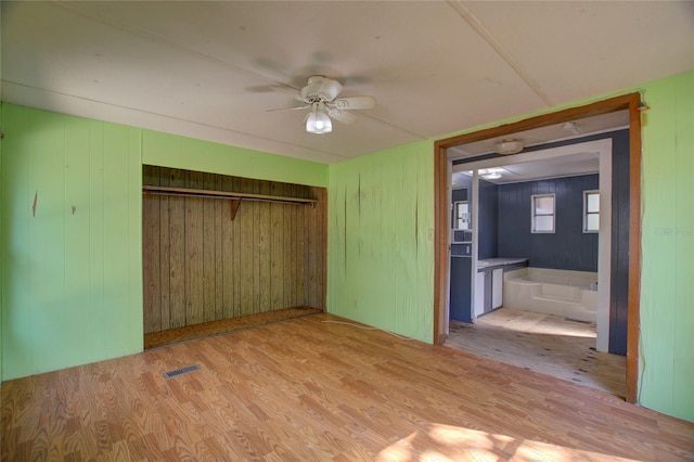 unfurnished bedroom with a closet, visible vents, ceiling fan, and wood finished floors