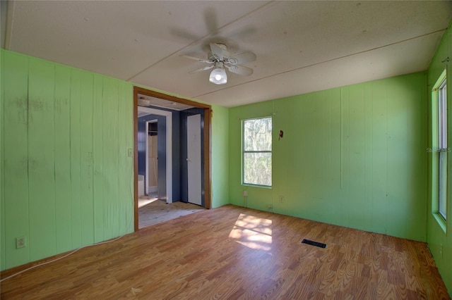 unfurnished room with a ceiling fan, visible vents, and wood finished floors