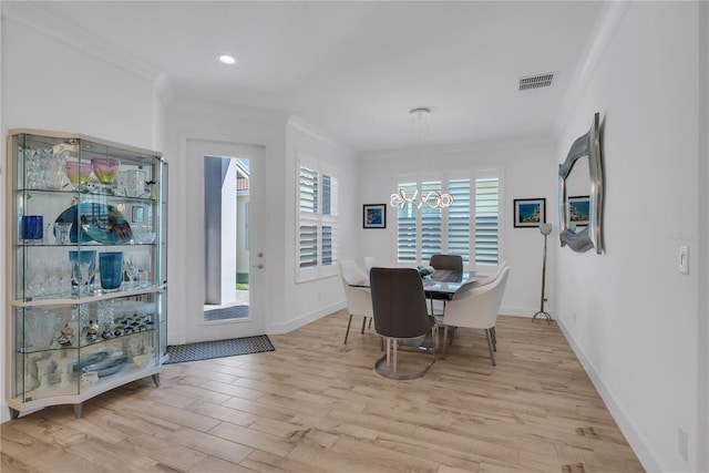 dining area with visible vents, light wood-style flooring, an inviting chandelier, ornamental molding, and baseboards