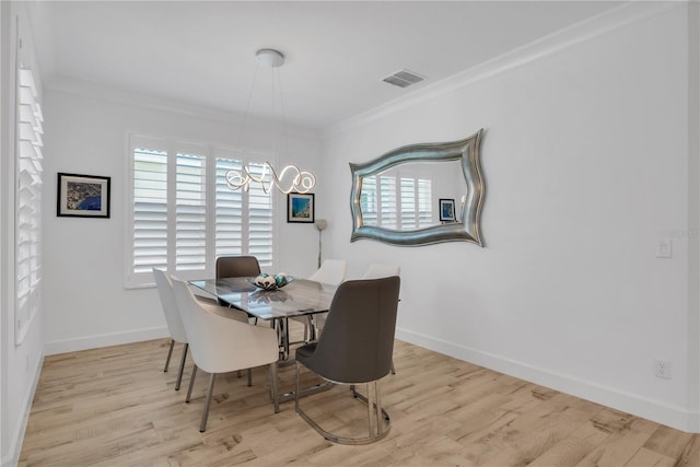 dining room featuring baseboards, visible vents, crown molding, and wood finished floors