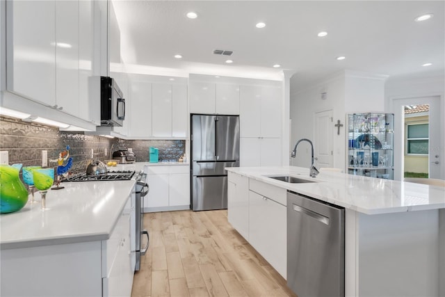 kitchen with a sink, white cabinetry, light wood-style floors, appliances with stainless steel finishes, and modern cabinets