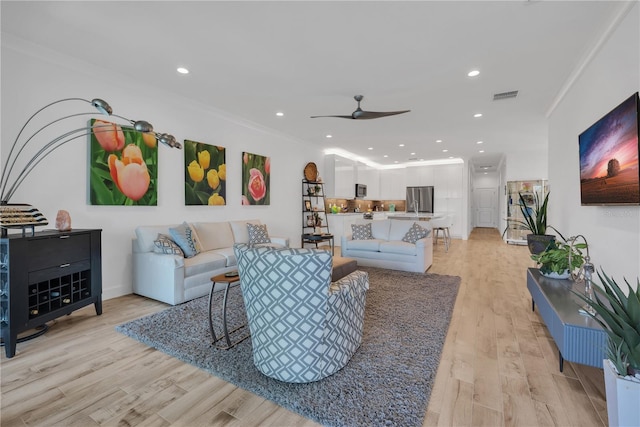 living room featuring visible vents, a ceiling fan, light wood-style flooring, ornamental molding, and recessed lighting