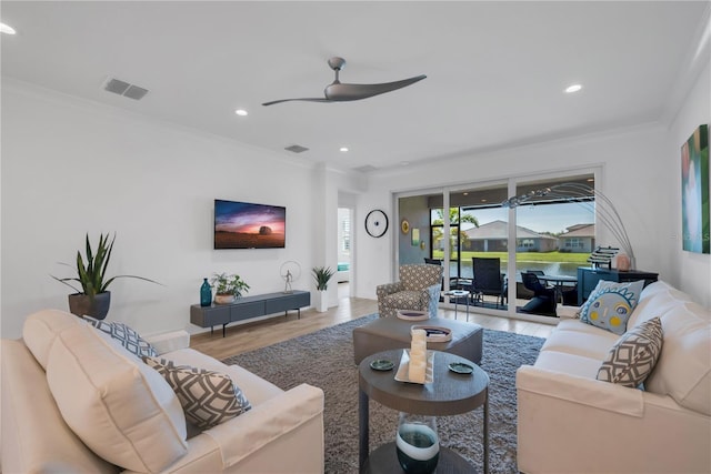 living room with ceiling fan, crown molding, visible vents, and wood finished floors