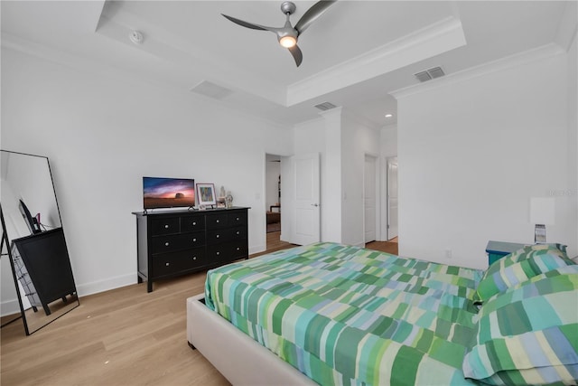 bedroom with ornamental molding, a tray ceiling, wood finished floors, and visible vents