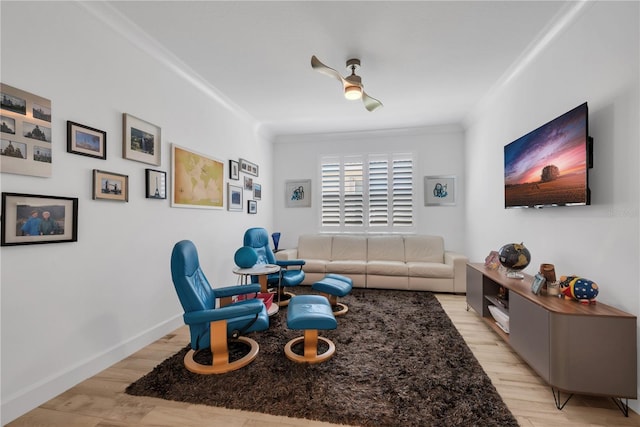 living area featuring baseboards, light wood-type flooring, and crown molding