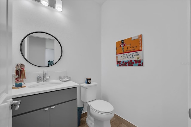 half bathroom featuring baseboards, vanity, and toilet