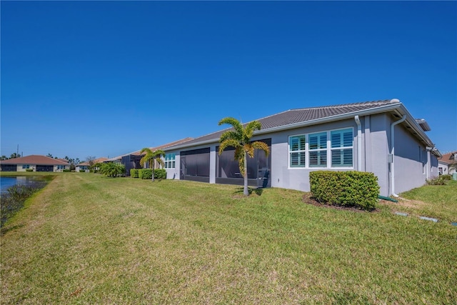 back of property featuring a sunroom, a lawn, and stucco siding