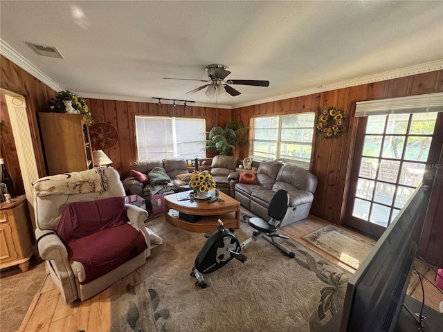 living area with ornamental molding, plenty of natural light, visible vents, and light wood-style floors