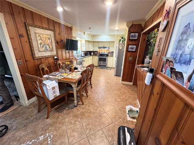 dining room featuring light tile patterned floors, ornamental molding, and wooden walls