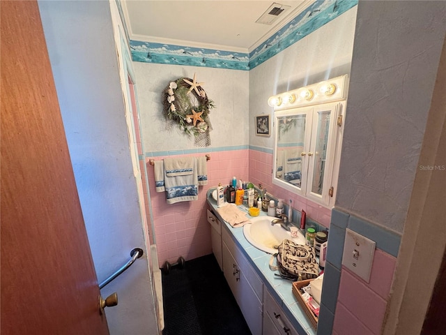 bathroom with wainscoting, visible vents, tile walls, and vanity