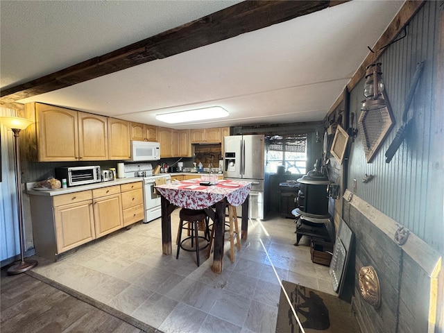 kitchen featuring white appliances, beamed ceiling, light countertops, a textured ceiling, and light brown cabinets