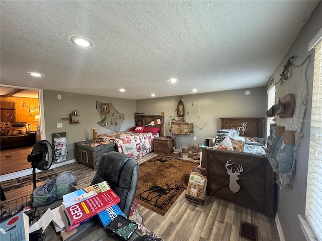 bedroom featuring visible vents, a textured ceiling, and wood finished floors