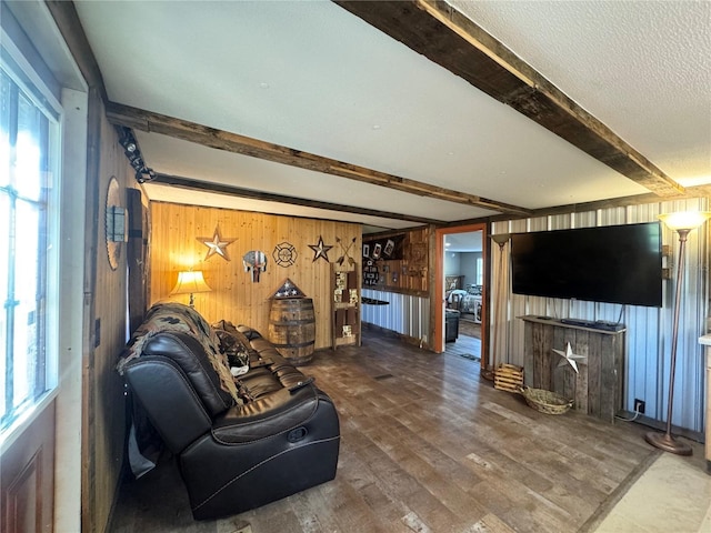 living room with plenty of natural light, wooden walls, beamed ceiling, and wood finished floors