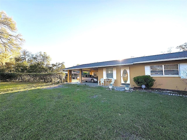 view of front facade featuring stucco siding, a carport, and a front yard