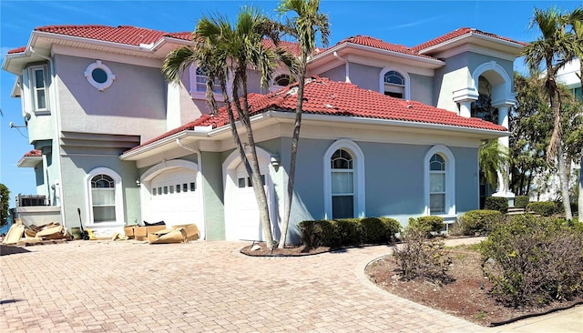 mediterranean / spanish-style house featuring decorative driveway, a tile roof, and stucco siding