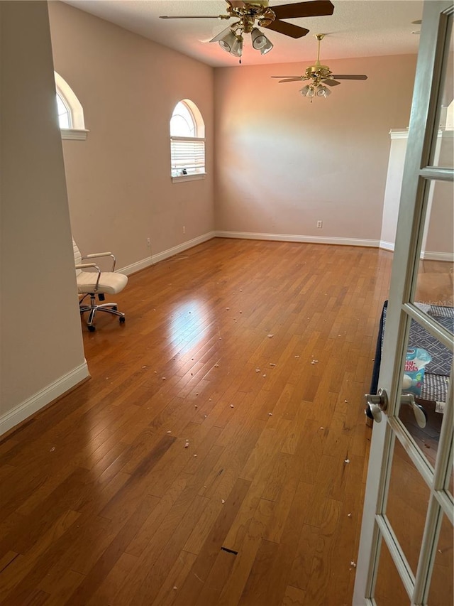 spare room with a ceiling fan, baseboards, and hardwood / wood-style floors