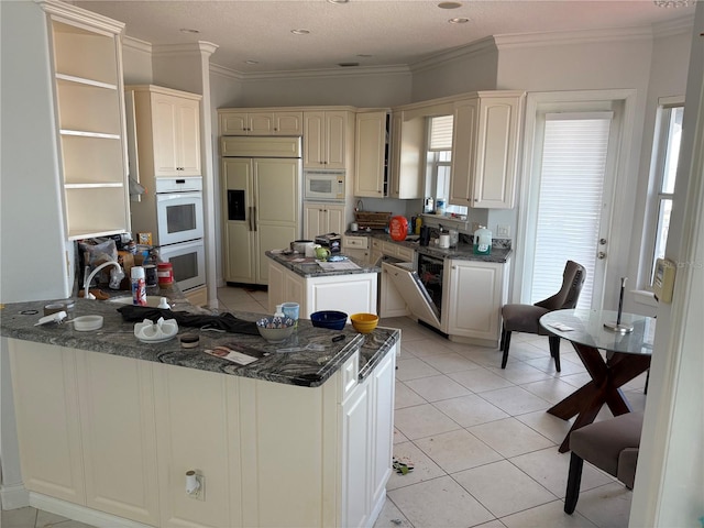 kitchen featuring ornamental molding, light tile patterned floors, a peninsula, and built in appliances