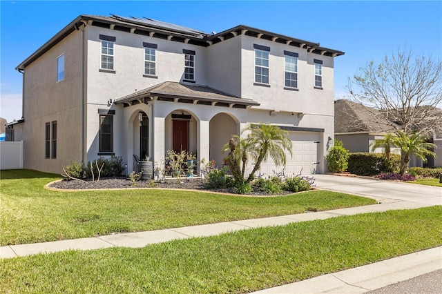 mediterranean / spanish-style house with driveway, a front yard, roof mounted solar panels, and stucco siding