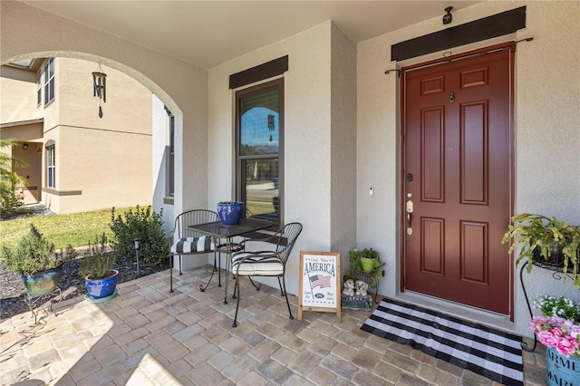 view of exterior entry with a patio and stucco siding