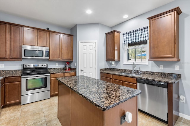 kitchen with recessed lighting, appliances with stainless steel finishes, a sink, a kitchen island, and dark stone countertops