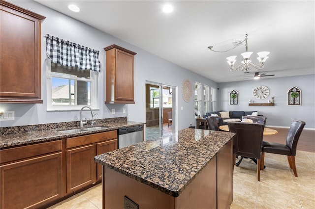 kitchen with open floor plan, stainless steel dishwasher, dark stone counters, and a sink