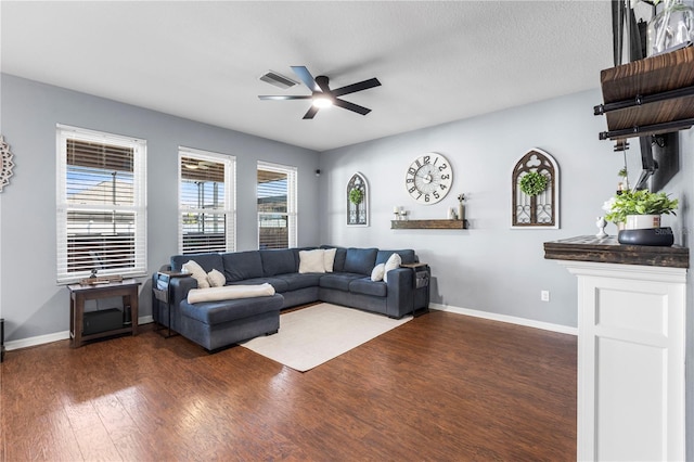 living room featuring ceiling fan, visible vents, baseboards, and dark wood-style flooring