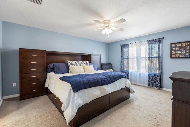 bedroom with baseboards, a ceiling fan, visible vents, and light colored carpet