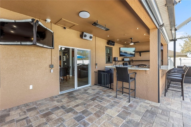 view of patio with ceiling fan, glass enclosure, fence, and outdoor wet bar