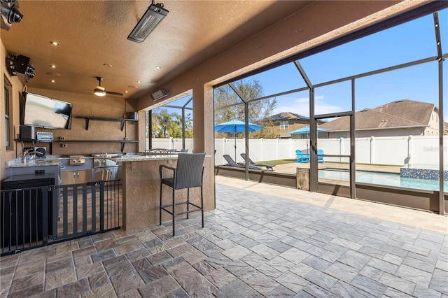 view of patio / terrace with an outdoor kitchen, a fenced in pool, a fenced backyard, a lanai, and outdoor wet bar